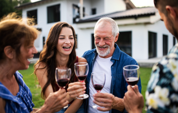 Portrait of people with wine outdoors on family garden barbecue, clinking glasses.