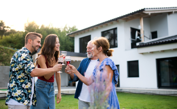 Portrait of people with wine outdoors on family garden barbecue, clinking glasses.