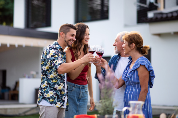 Portrait of people with wine outdoors on family garden barbecue, clinking glasses.