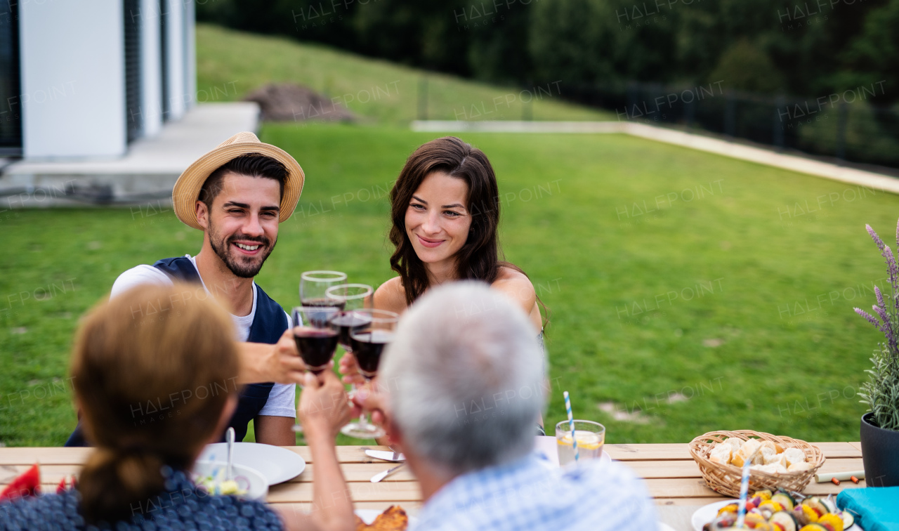 Portrait of people with wine outdoors on family garden barbecue, clinking glasses.