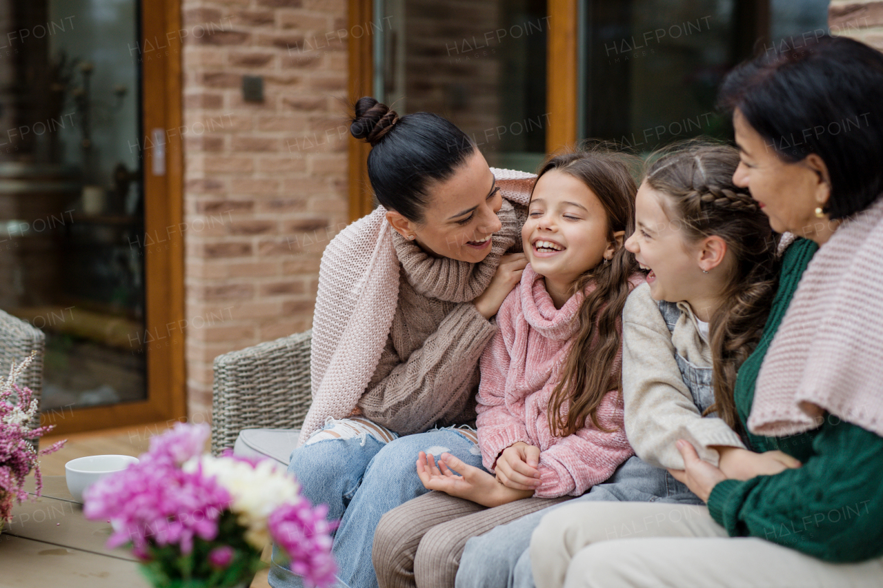 Three generations females sitting outdoors in a patio in autumn