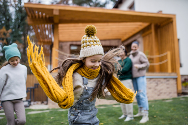 Two happy sisters with a mother and grandmother playing and running outdoors in garden in autumn