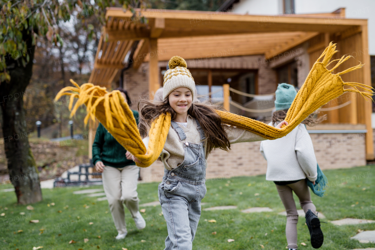 Two happy sisters with a mother and grandmother playing and running outdoors in garden in autumn