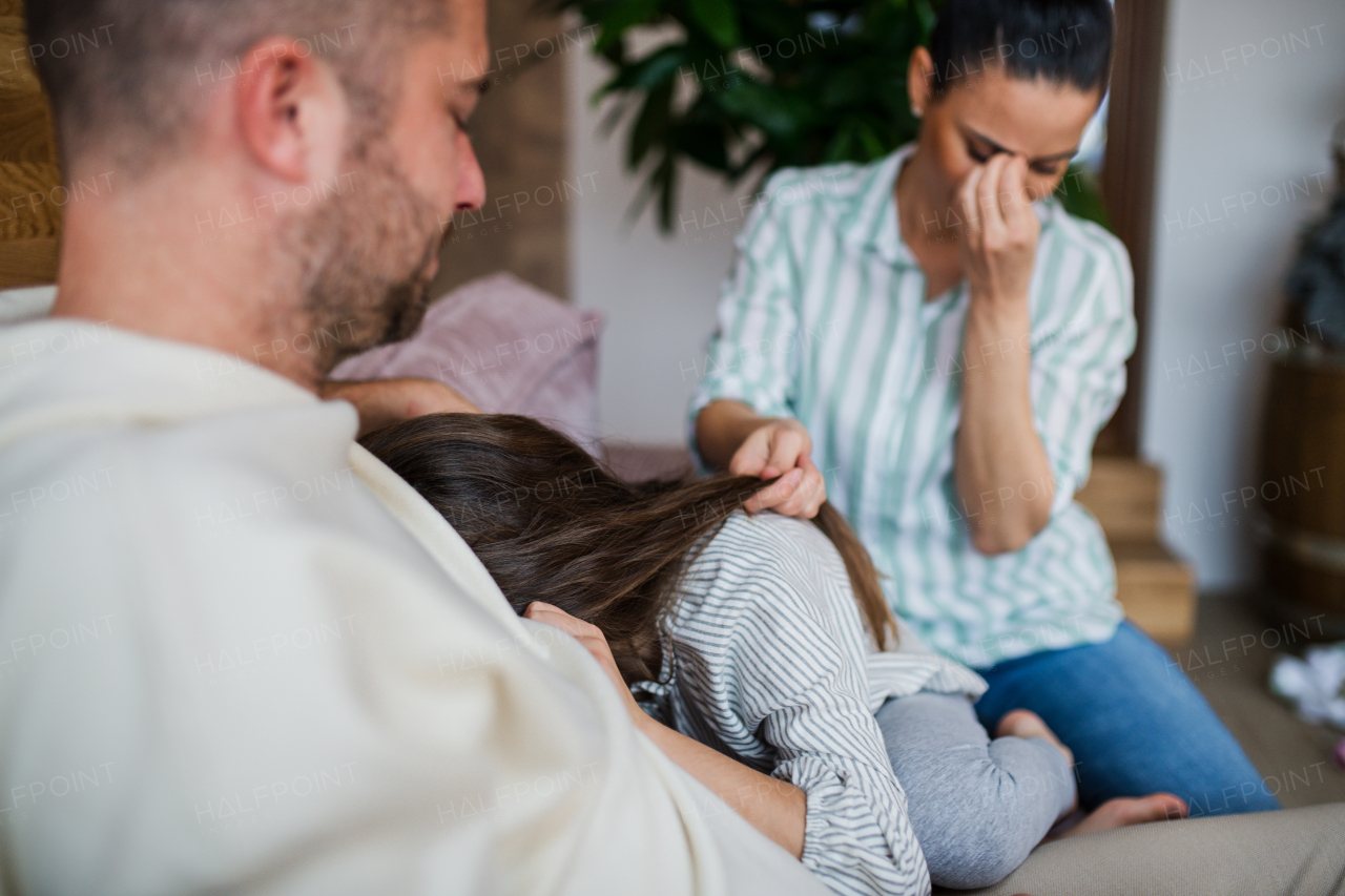 A worried mother and father consling little daughter at home