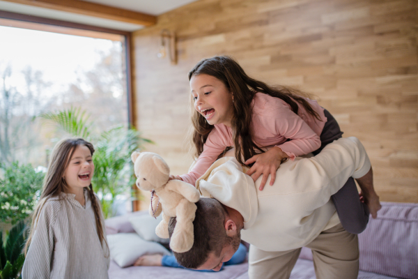 Two happy sisters having fun with a father at home