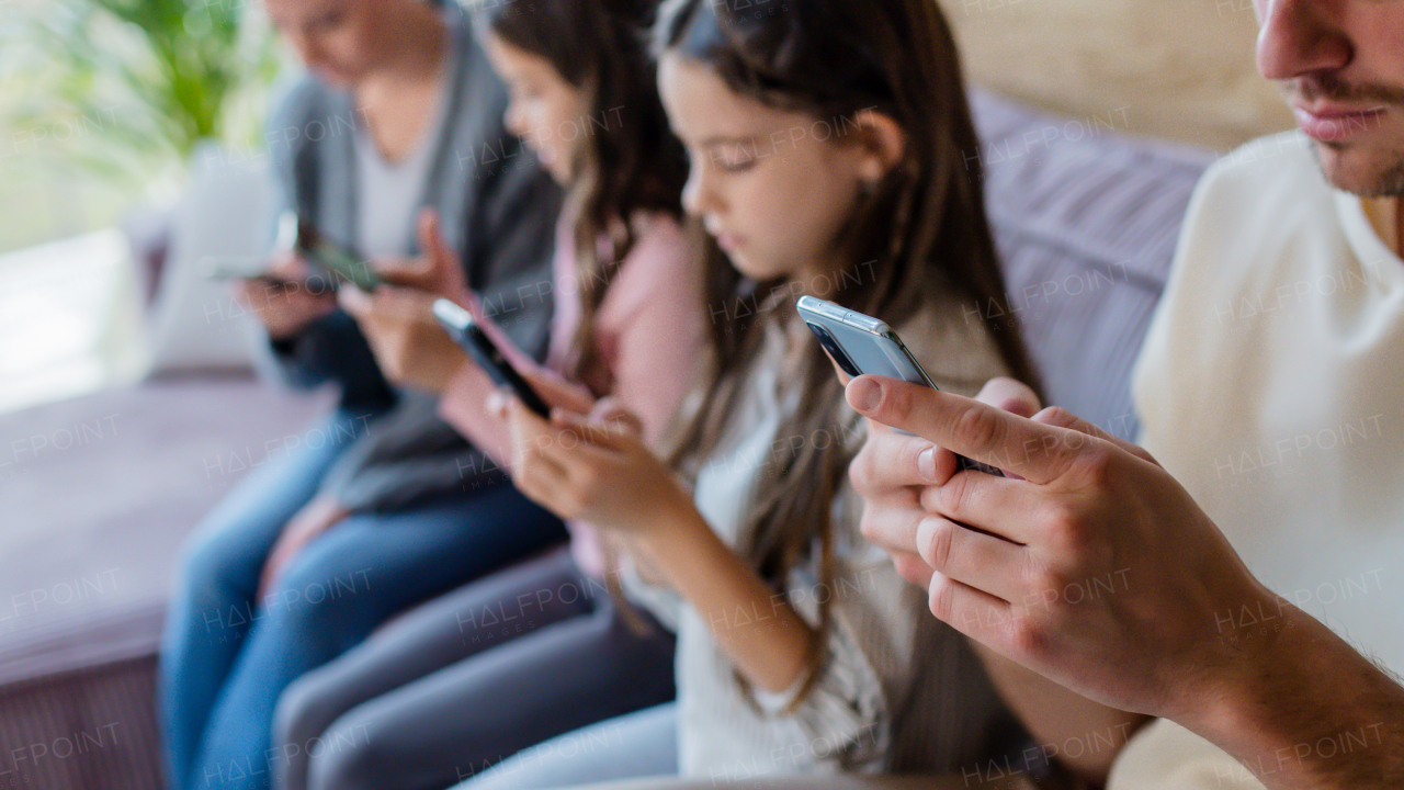 A family with two little daughters, everyone is using mobile phone in the living room.