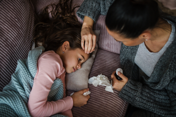 A high angle view of mother taking care of her sick daughter at home.