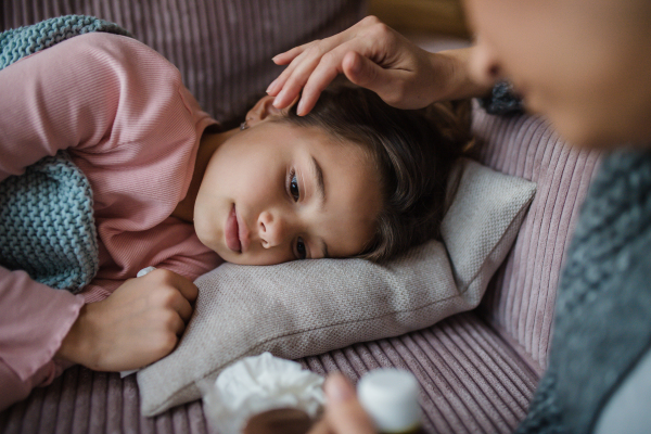 A mother taking care of her sick daughter at home.