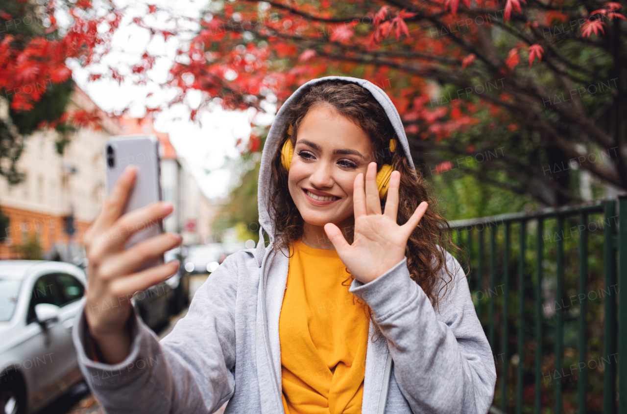 Portrait of young woman with smartphone outdoors on street, video for social media concept.