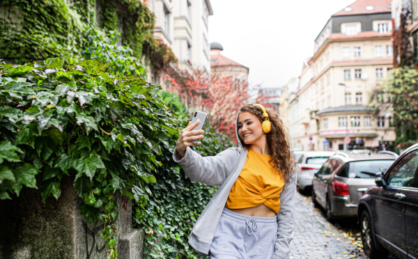 Portrait of young woman with smartphone outdoors on street, video for social media concept.