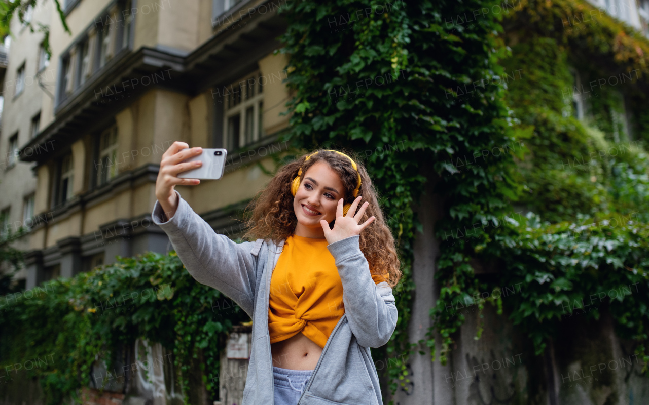 Portrait of young woman with smartphone outdoors on street, video for social media concept.