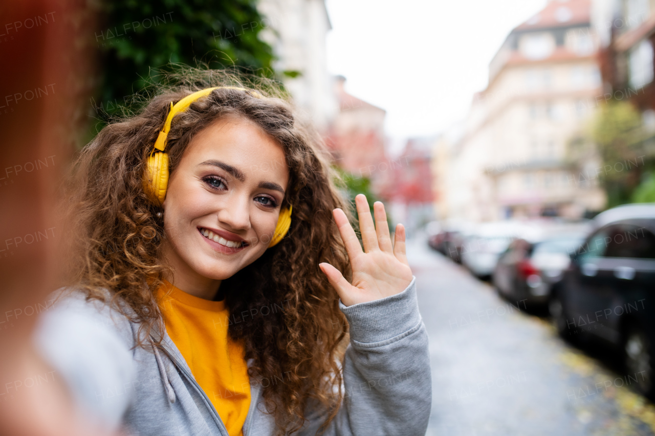 Portrait of young woman with smartphone outdoors on street, video for social media concept.