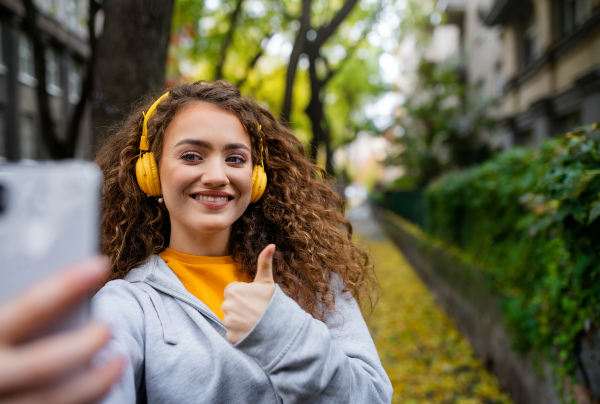 Portrait of young woman with smartphone outdoors on street, video for social media concept.