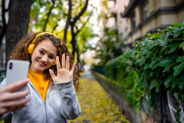 Portrait of young woman with smartphone outdoors on street, video for social media concept.