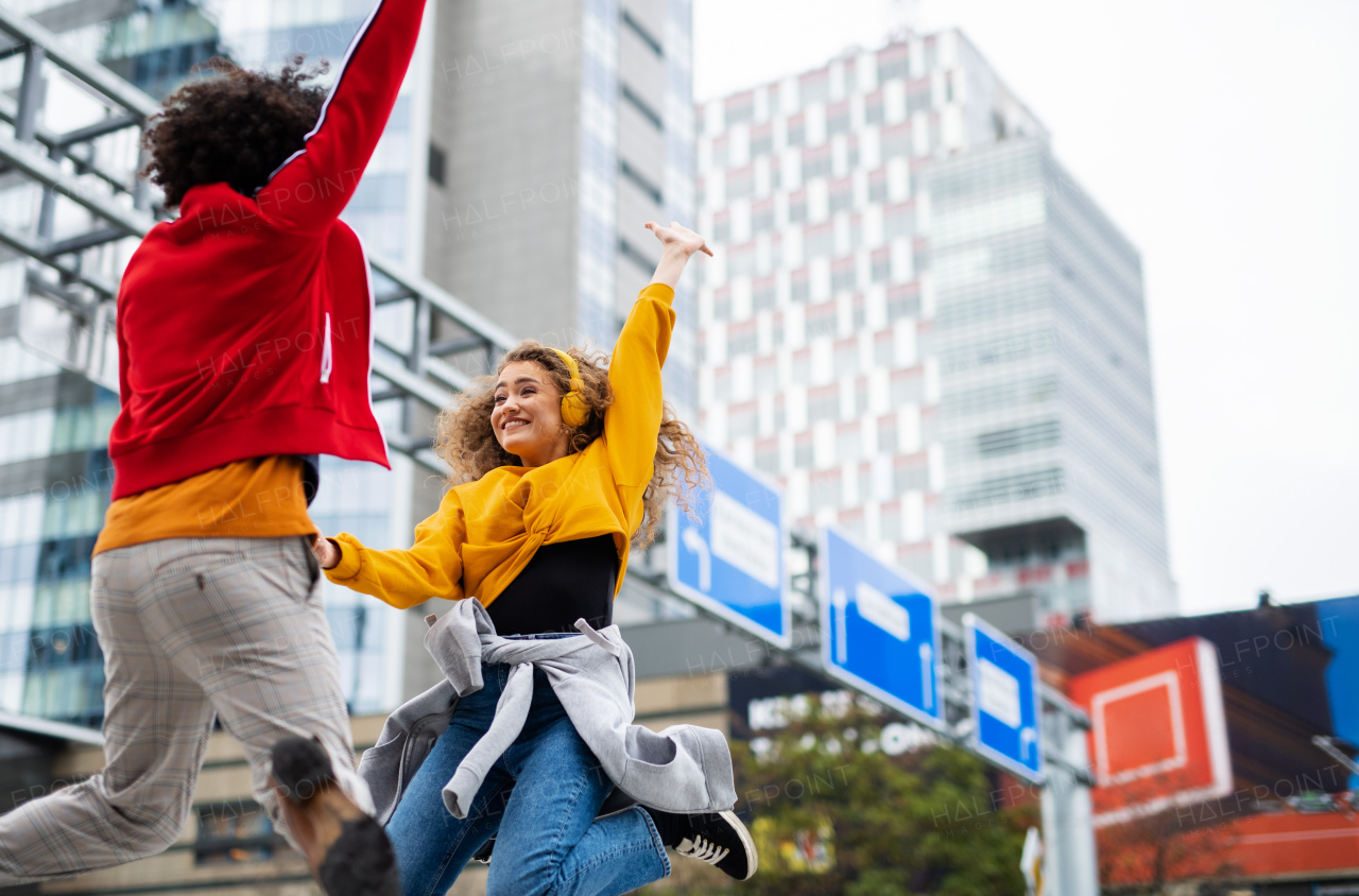 Young couple making video for social media outdoors on street, jumping. Copy space.