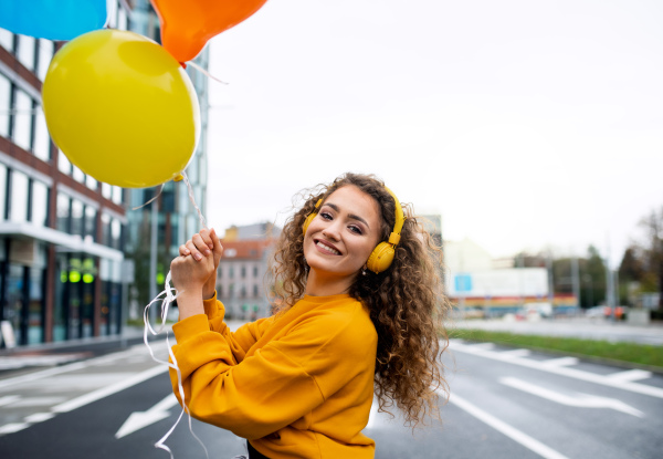 Portrait of young woman with balloons outdoors on street, video for social media concept.