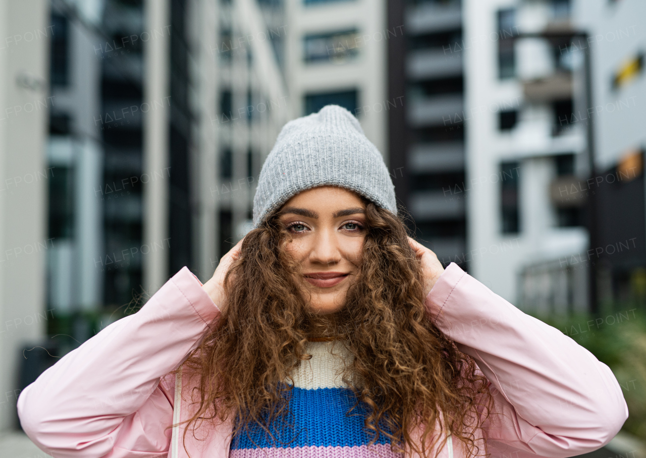 Portrait of young woman outdoors on street, looking at camera.