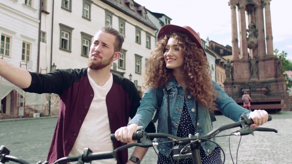 Young tourist couple travellers with electric scooters in small town, sightseeing.