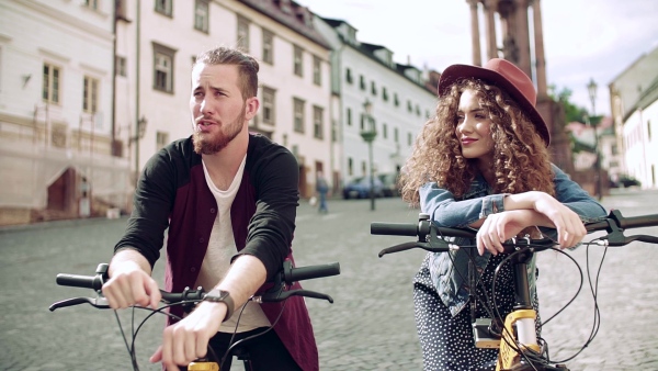 Young tourist couple travellers with electric scooters in small town, sightseeing. Slow motion.