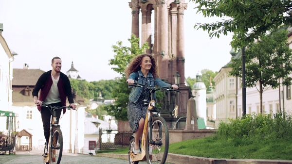 Young tourist couple travellers with electric scooters in small town, sightseeing. Slow motion.