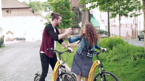 Young tourist couple travellers with electric scooters in small town, sightseeing. Slow motion.