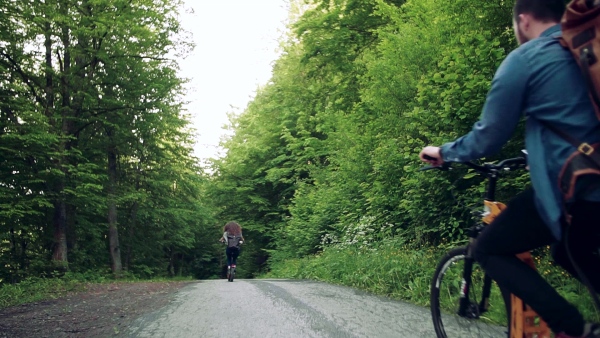 Rear view of young tourist couple travellers with backpacks and electric scooters in nature. Slow motion.