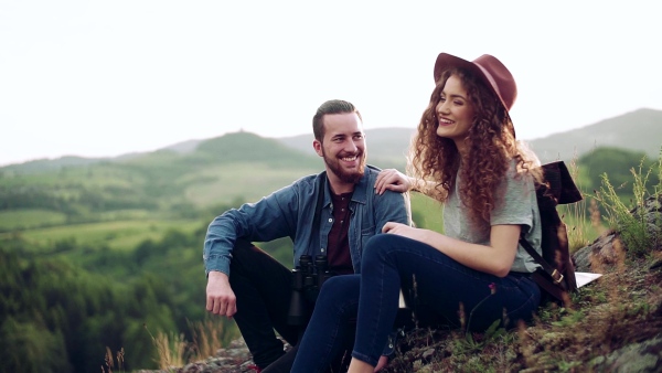 Young tourist couple travellers hiking in nature, sitting and resting. Slow motion.