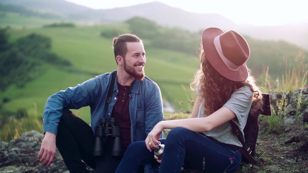 Young tourist couple travellers hiking in nature, sitting and resting. Slow motion.