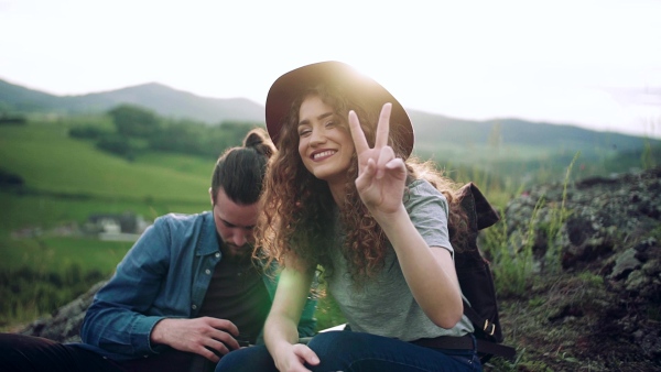 Young tourist couple travellers hiking in nature, sitting and resting. Slow motion.