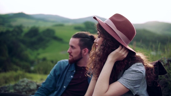 Young tourist couple travellers hiking in nature, sitting and resting. Slow motion.