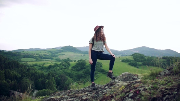 A young tourist woman traveller with backpack standing in nature. Slow motion.