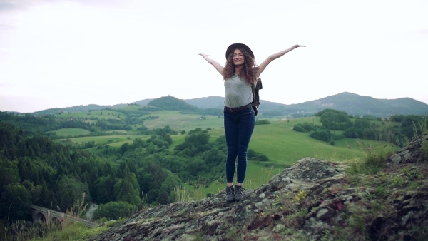 A young tourist woman traveller with backpack standing in nature. Slow motion.