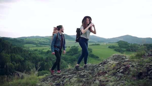 A young tourist couple travellers with backpacks hiking in nature. Slow motion.