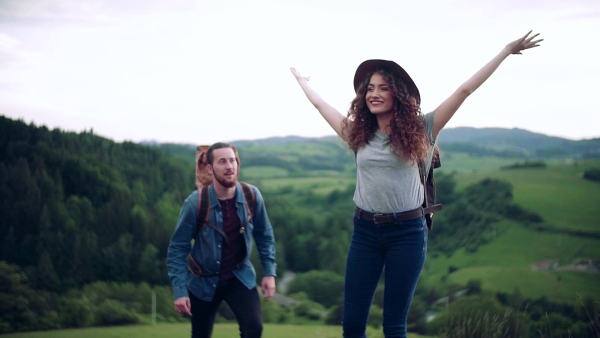 A young tourist couple travellers with backpacks hiking in nature. Slow motion.