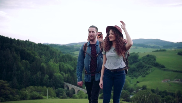 A young tourist couple travellers with backpacks hiking in nature. Slow motion.