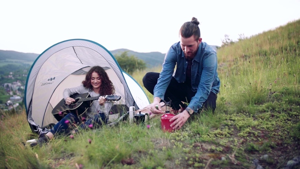 A young tourist couple travellers with tent shelter sitting in nature, resting. Slow motion.