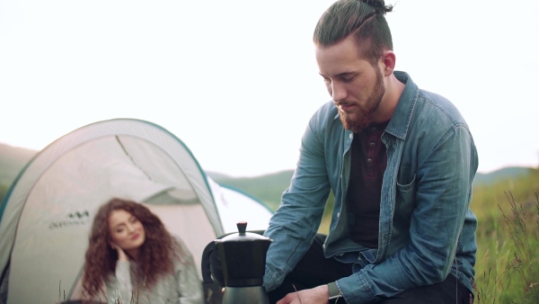 A young tourist couple travellers with tent shelter sitting in nature, resting. Slow motion.