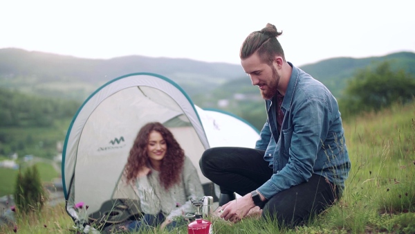 A young tourist couple travellers with tent shelter sitting in nature, resting. Slow motion.