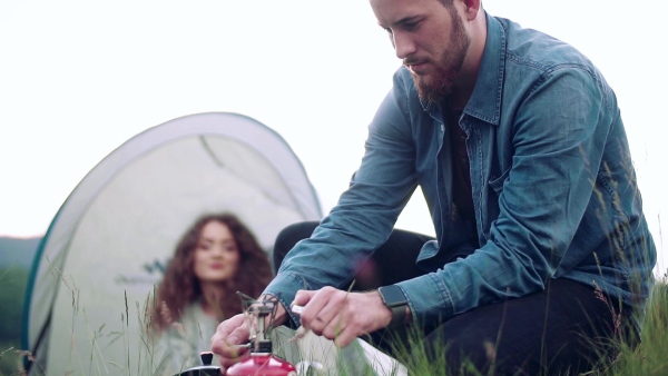 A young tourist couple travellers with tent shelter sitting in nature, resting. Slow motion.