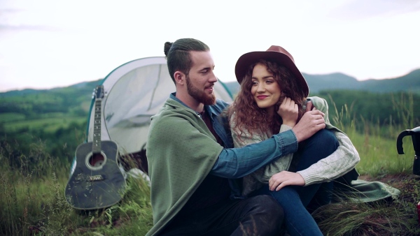 A young tourist couple travellers with tent shelter sitting in nature, resting. Slow motion.