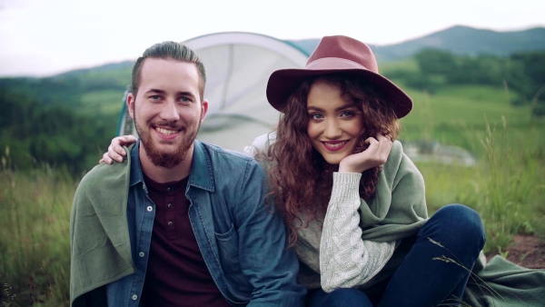 A young tourist couple travellers with tent shelter sitting in nature, resting. Slow motion.