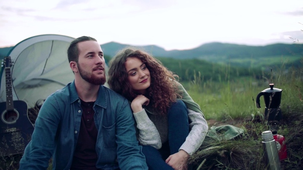 A young tourist couple travellers with tent shelter sitting in nature, resting. Slow motion.