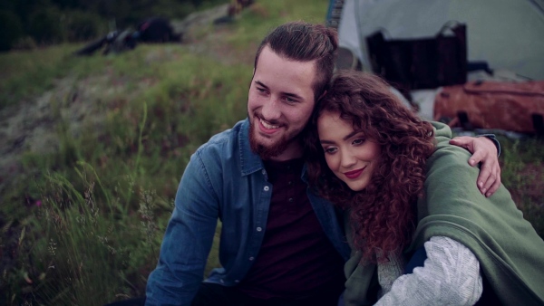 A young tourist couple travellers with tent shelter sitting in nature, resting. Slow motion.