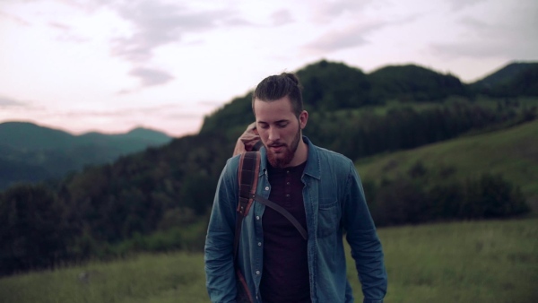 Young man tourist traveller with backpack hiking in nature, walking. Slow motion.