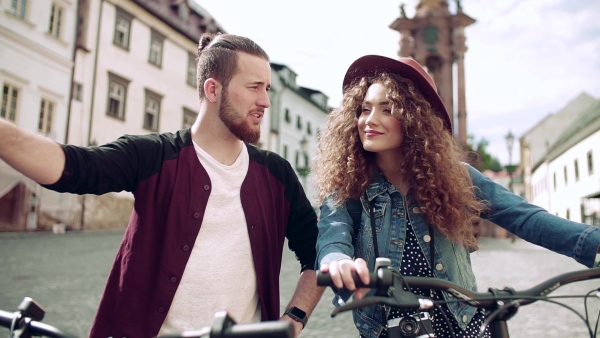 Young tourist couple travellers with electric scooters in small town, sightseeing. Slow motion.