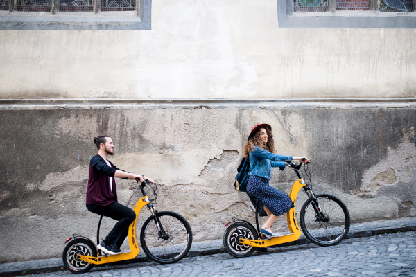 Young tourist couple travellers with electric scooters in small town, sightseeing.