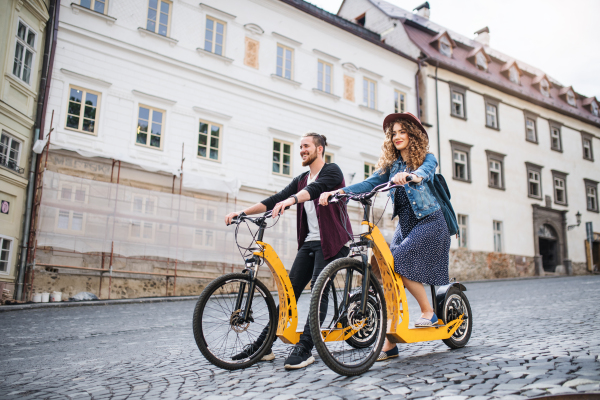 Young tourist couple travellers with electric scooters in small town, sightseeing.