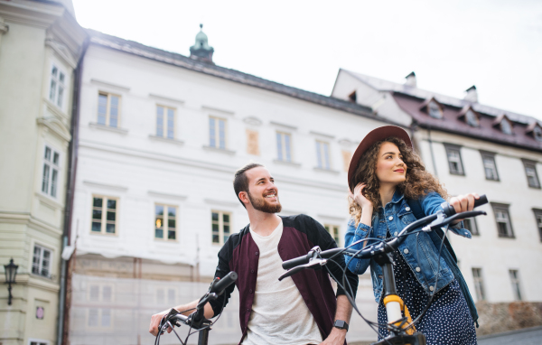 Young tourist couple travellers with electric scooters in small town, sightseeing.