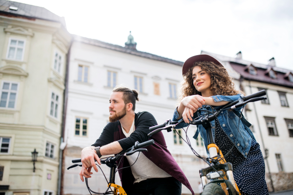 Young tourist couple travellers with electric scooters in small town, sightseeing.