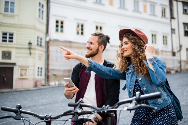 Young tourist couple travellers with smartphone and electric scooters in small town, sightseeing.